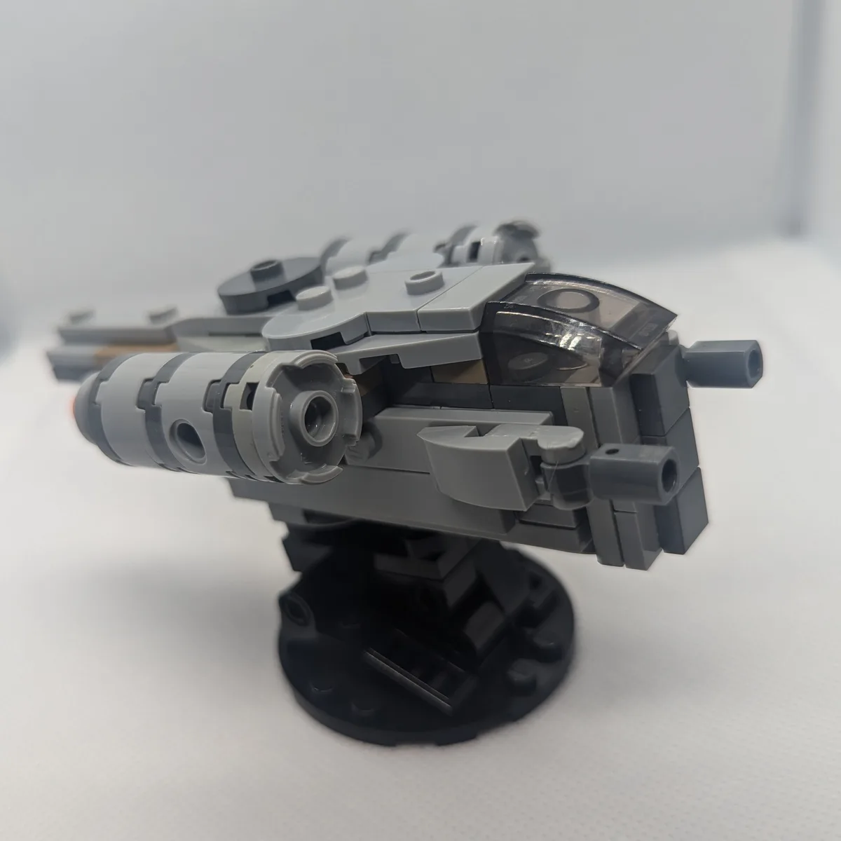 A close-up photo of a gray Lego Star Wars spaceship model, likely a TIE fighter or similar, displayed on a black circular…