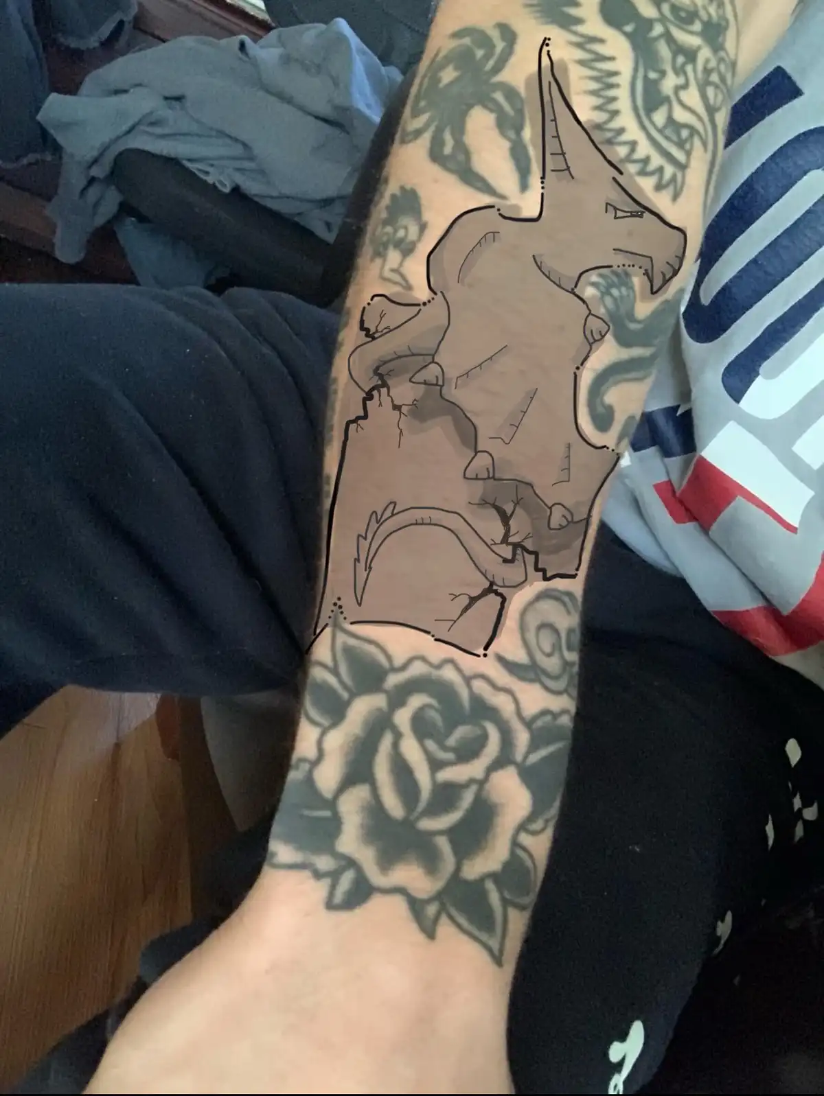 A person's forearm displays multiple tattoos, including a large, unfinished outline of a dog's head and body, with visible…