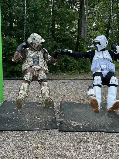 Two people in full Star Wars costume — one in a camo Clone Trooper outfit and the other in a white Stormtrooper outfit — are…