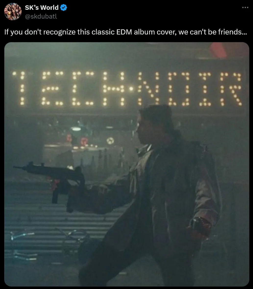 A person in a dark coat is shown holding a machine gun in a gritty, dimly lit environment. Behind them, a large digital sign…