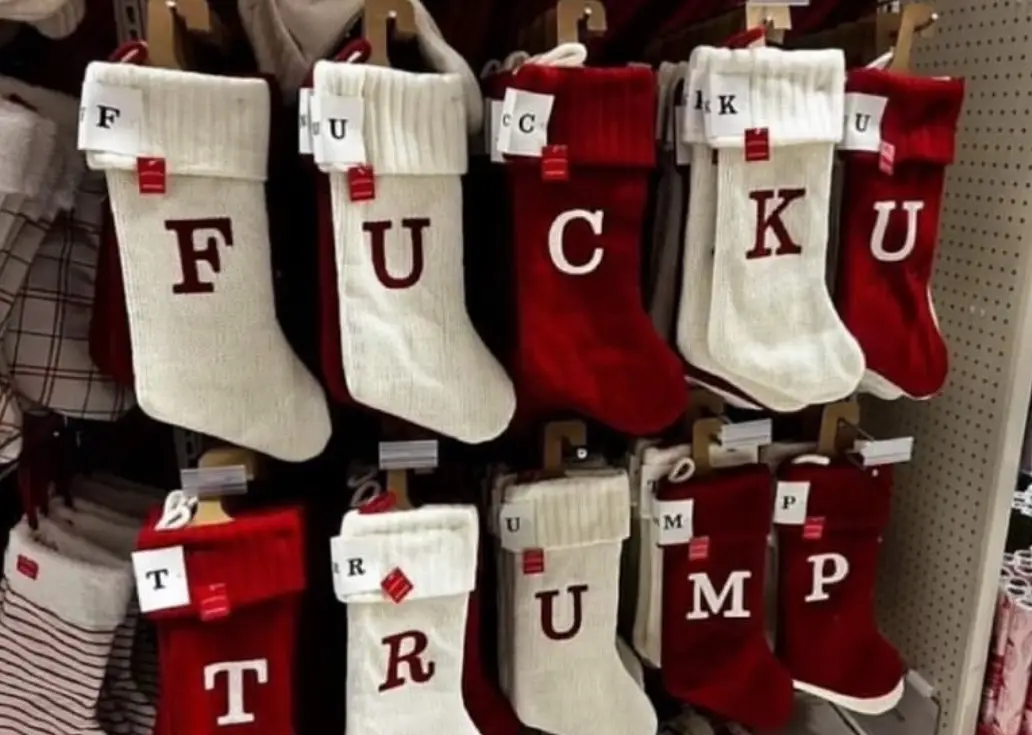 A store display of red and white Christmas stockings, each with a large letter on the front spelling out 'FUCK YOU TRUMP'…