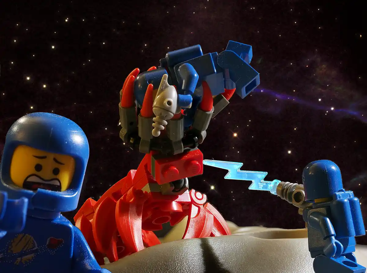 A LEGO minifigure with a terrified expression stands beside a large, menacing red and blue LEGO robot in space. Another LEGO…