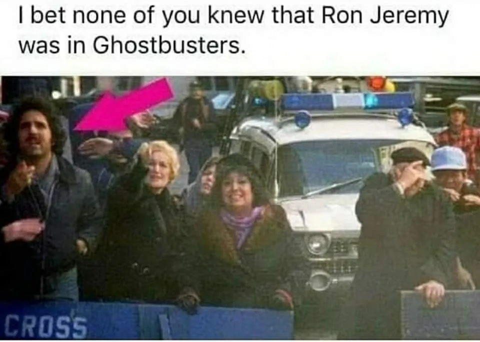 A still from the movie Ghostbusters shows a crowd of people watching an event, with a police car in the background. A bright…