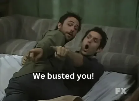 Two men are lying on a couch, both pointing excitedly at something off-screen with shocked expressions. The man in the…