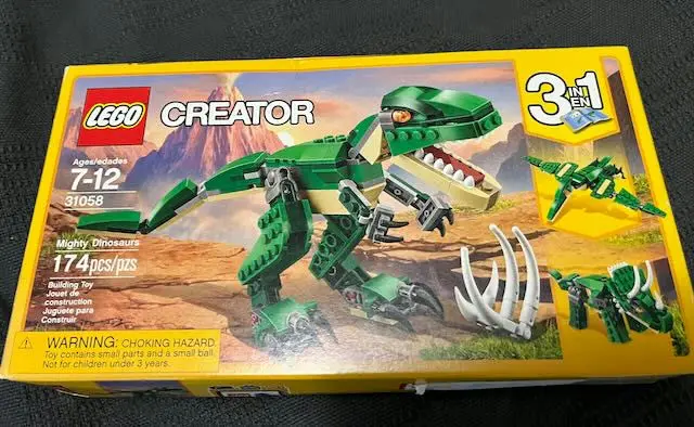 A LEGO Creator box for set 31058 'Mighty Dinosaurs' shows a green LEGO dinosaur model with sharp claws and teeth, set…