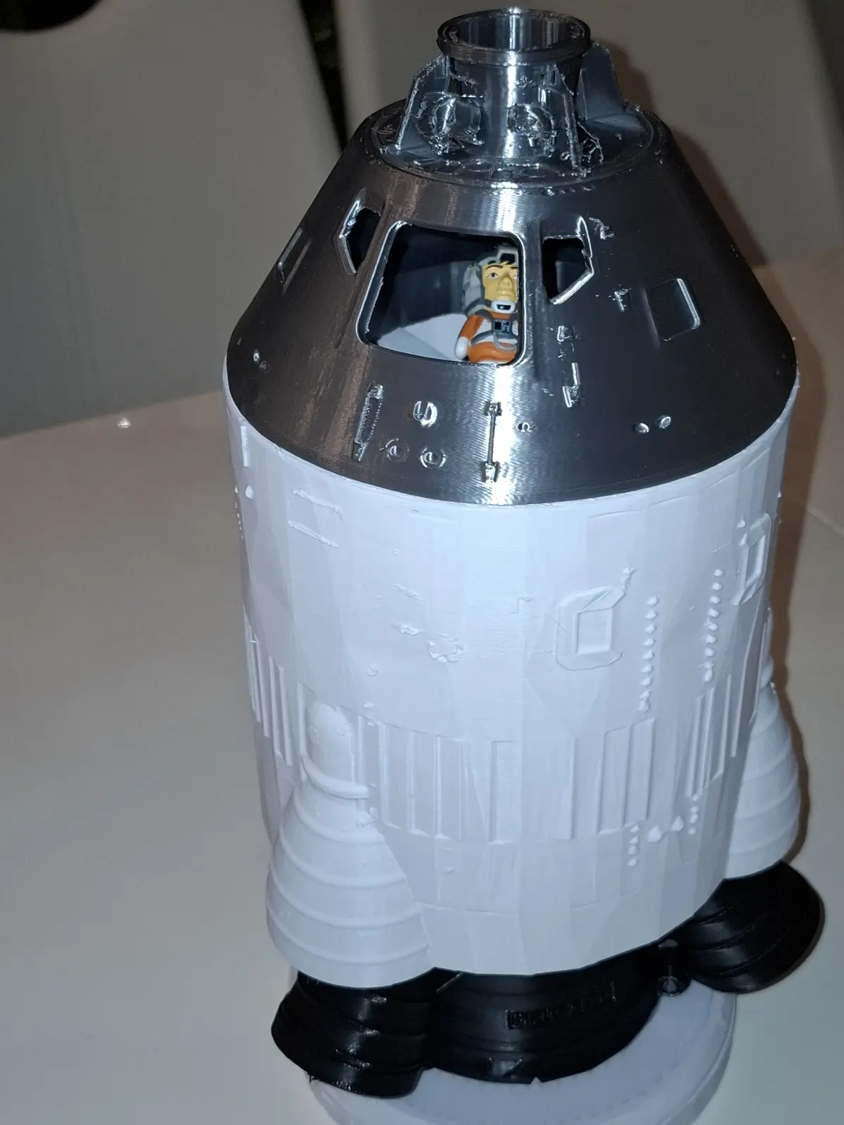 A 3D-printed model of a spacecraft, resembling a SpaceX Dragon capsule, has a small figurine of the animated character…