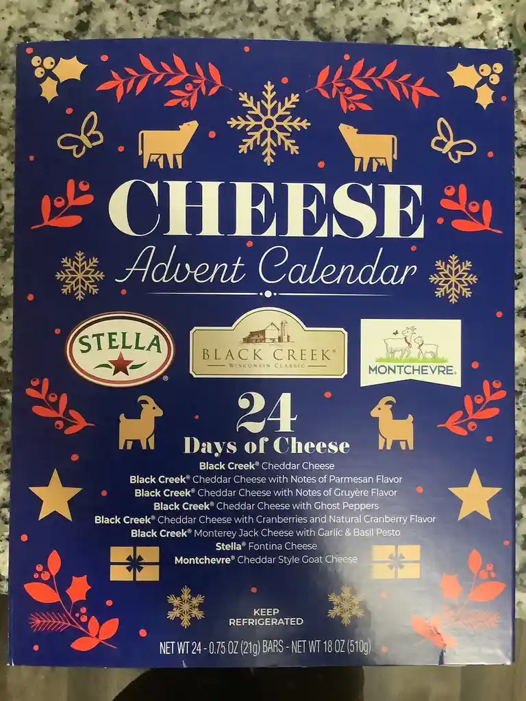 A blue cheese advent calendar box decorated with red and gold holiday motifs like snowflakes, holly, and goats. The box…