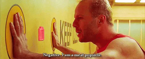 A man in a red tank top presses his hands against a yellow wall with circular targets, repeating the phrase 'Negative. I am…