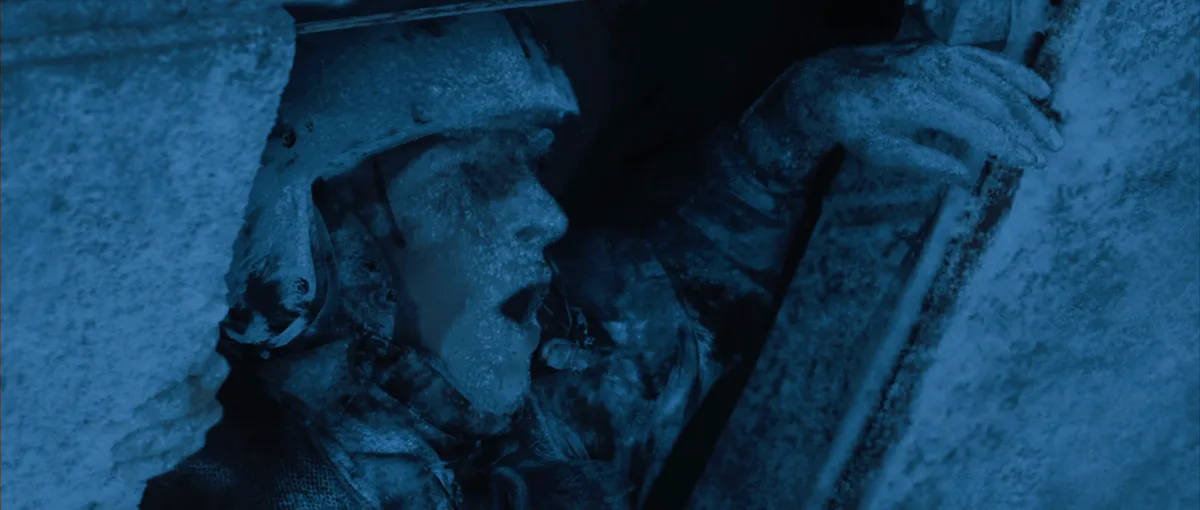 A soldier in a helmet and uniform is shown frozen solid in a snowy, icy environment, mouth open as if screaming or gasping…