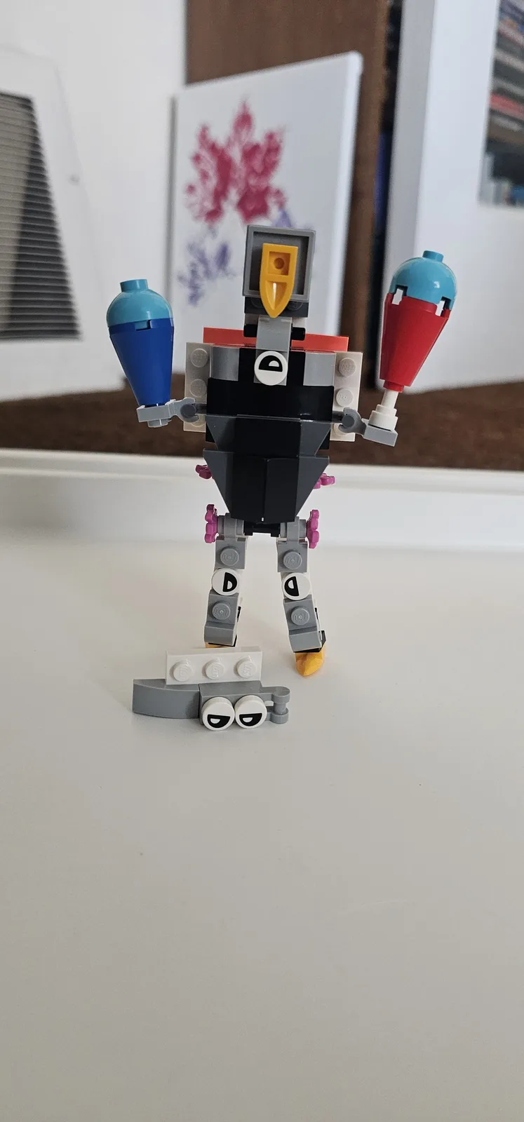 A LEGO robot figure stands upright on a white surface, holding two colorful cone-shaped objects, with a pair of LEGO eyes…