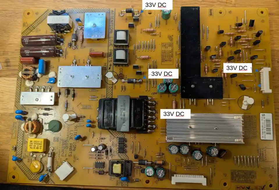 A yellow circuit board with various electronic components like capacitors, resistors, and heat sinks is shown on a wooden…
