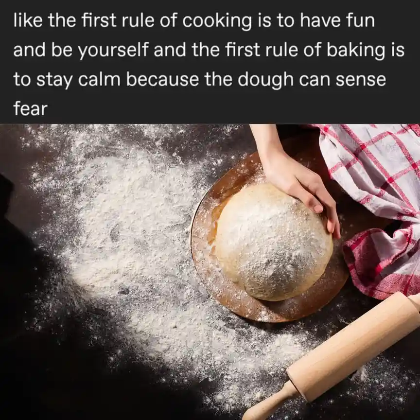 A top-down photo shows a person's hand holding a round ball of flour-dusted dough on a wooden board, surrounded by scattered…