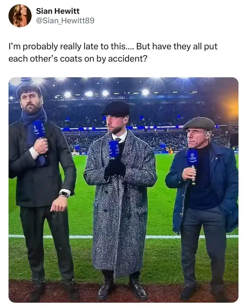 Three men stand on a football pitch holding microphones, each wearing a different coat that appears mismatched with their…