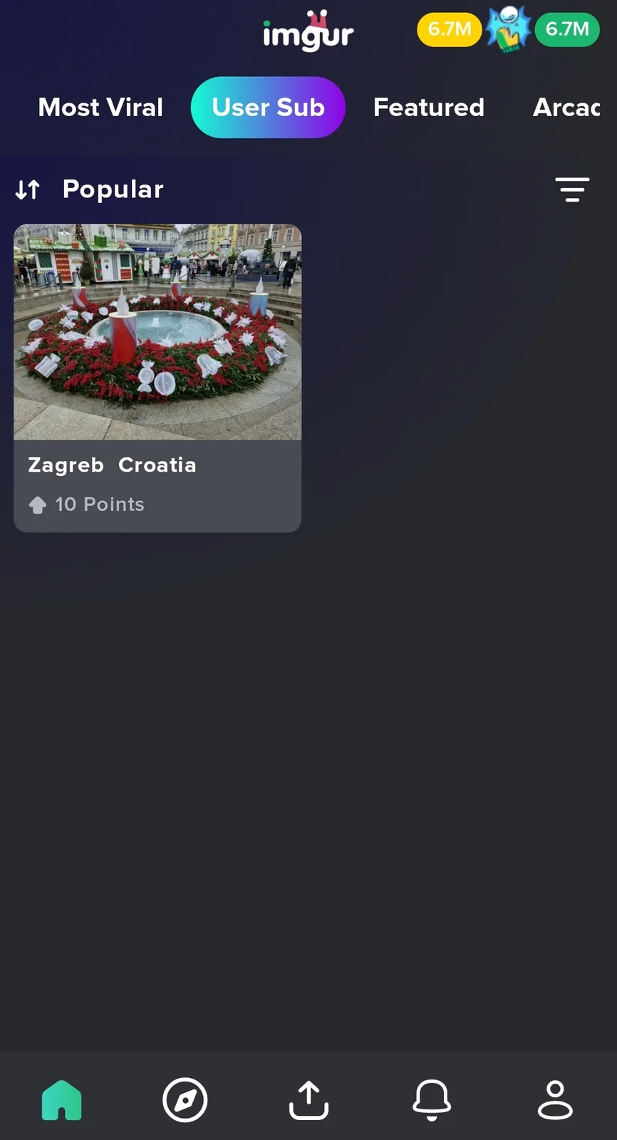 The image shows a festive Christmas wreath made of red flowers and white ornaments, arranged around a circular fountain in a…