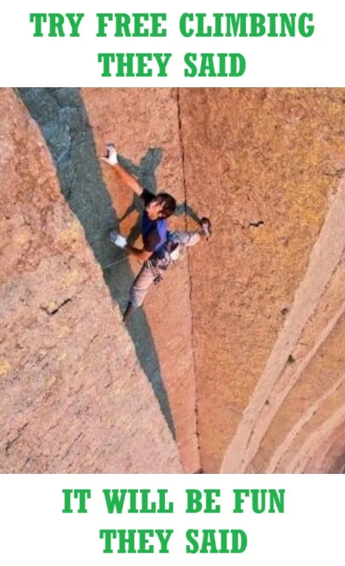 An aerial view shows a person in climbing gear scaling a steep, reddish-brown rock face, with their shadow cast below. The…