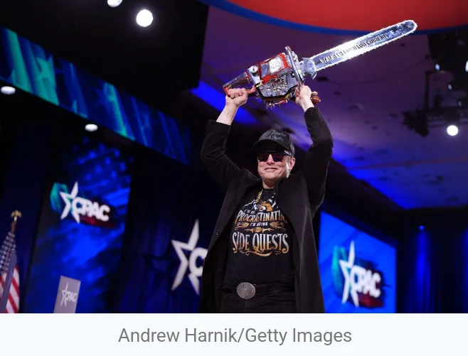 A man in a black jacket and cap holds up a large chainsaw trophy on a stage with 'CPAC' logos in the background. The image…