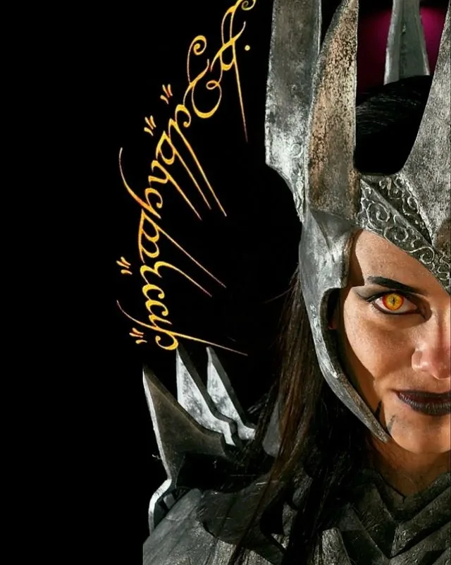 A close-up of a female character in dark, ornate armor with a helmet featuring pointed horns, her face partially visible…