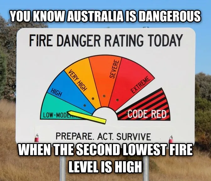 A public fire danger rating sign shows a color-coded scale with levels from 'Low-Moderate' to 'Code Red'. The yellow pointer…