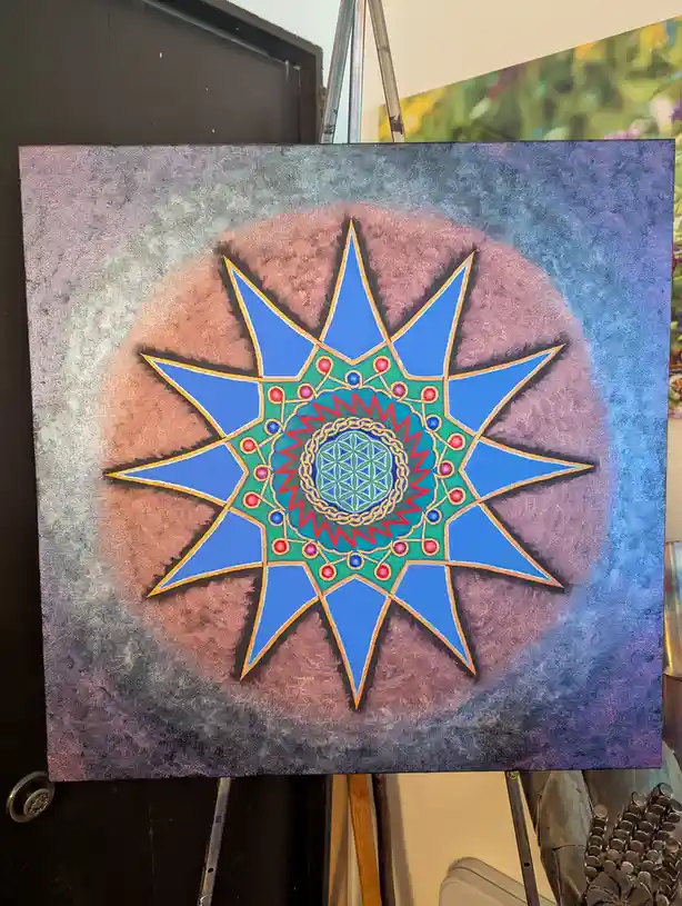 A colorful, intricate mandala-style painting on canvas, featuring a blue starburst pattern with a green center containing a…