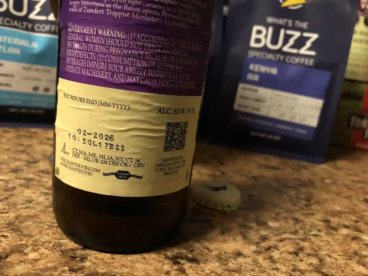 A close-up photo of a beer bottle's label showing a government warning about alcohol consumption, with a coffee bag labeled…