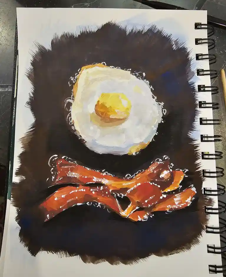 A painting in a spiral-bound sketchbook depicts a fried egg and crispy bacon arranged to resemble a face, with the egg as…