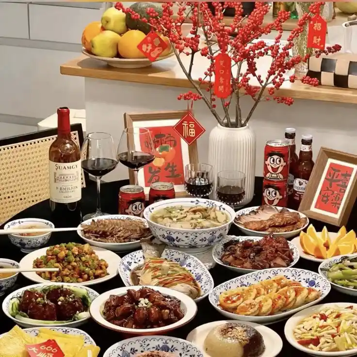 A lavish Chinese New Year feast is displayed on a black table, laden with numerous dishes including braised meats…