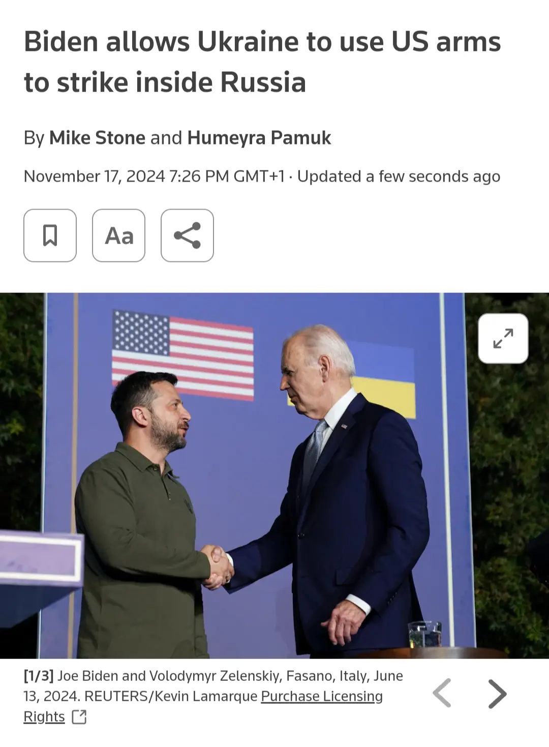 A screenshot of a news article header showing a photo of Joe Biden and Volodymyr Zelenskyy shaking hands in front of…