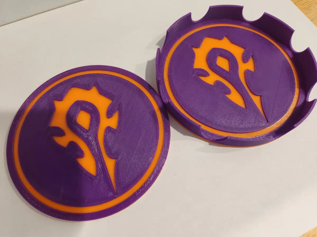 Two 3D-printed purple and orange circular objects, resembling bottle caps, feature the stylized 'S' logo of the video game…