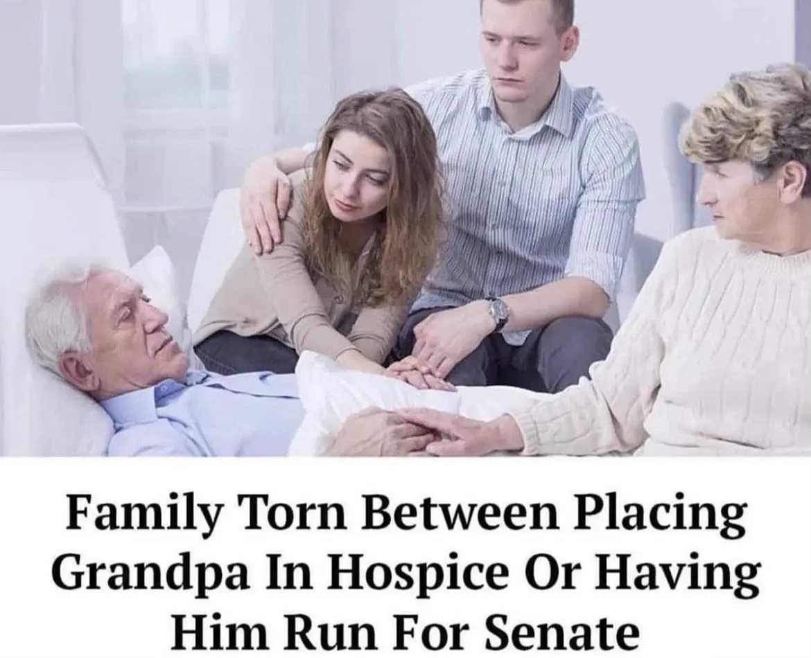 An elderly man lies in a hospital bed, surrounded by three family members — a woman and two men — all looking somber and…
