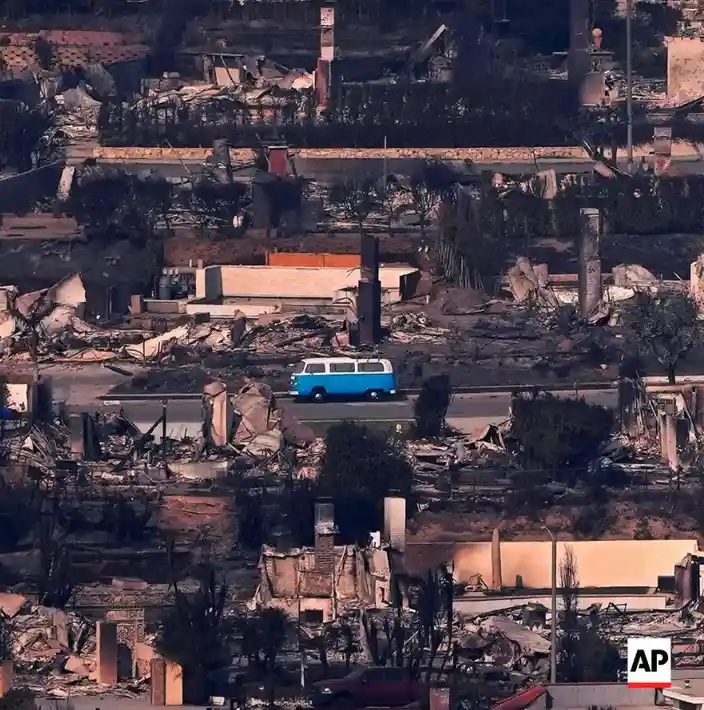 an aerial view shows a blue and white van driving down a road through a neighborhood completely destroyed by fire, with…