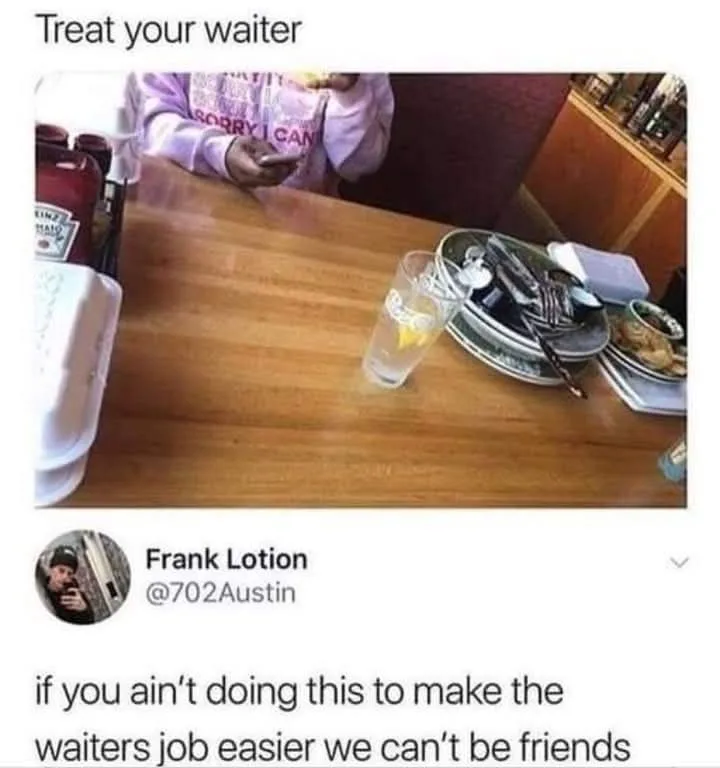 A person in a pink hoodie sits at a restaurant table, eating while looking at their phone. The table has empty plates…