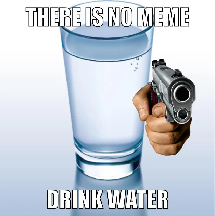 A hand holds a silver handgun pointed directly at a tall glass of clear water, which has a few bubbles rising. The image has…