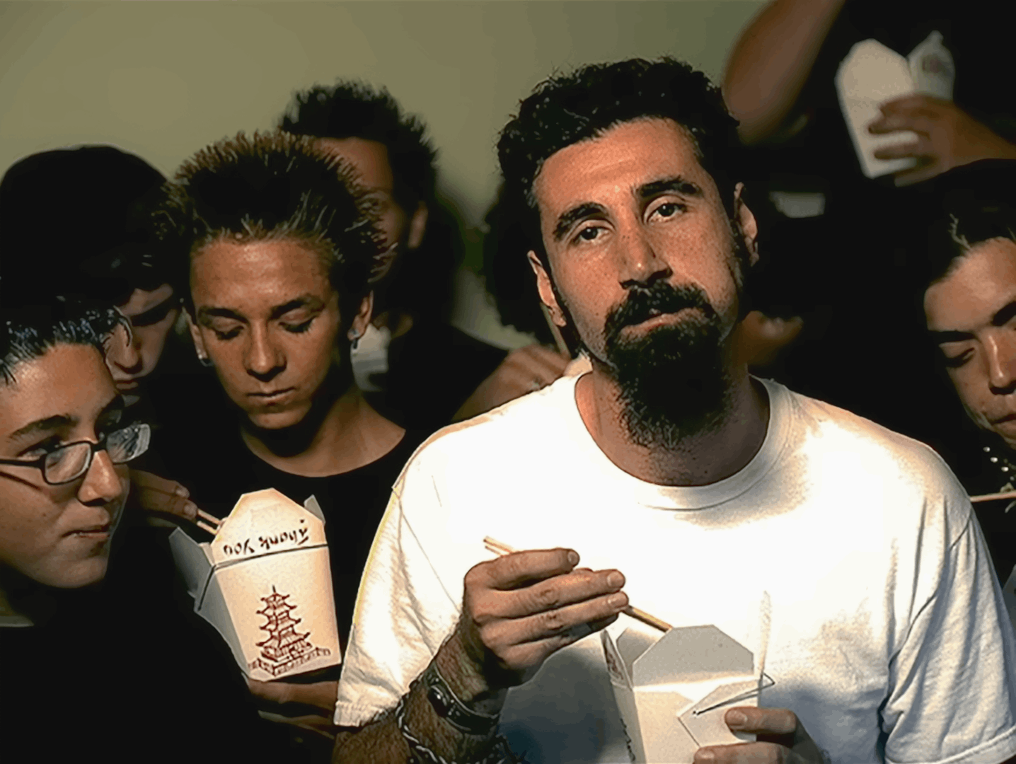 The image displays six panels of a man with a beard and white t-shirt holding a takeout container and chopsticks, looking…