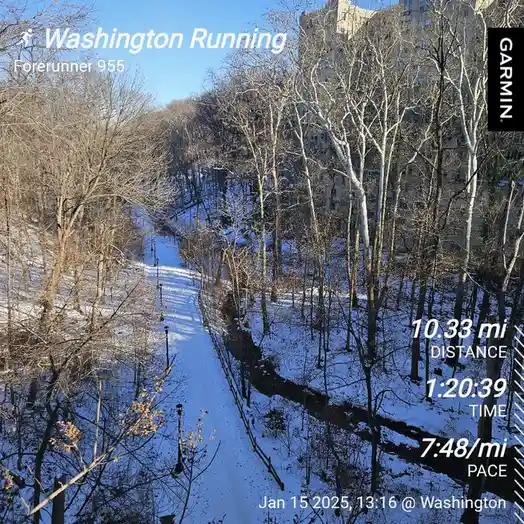 A snowy trail through bare trees with a large building in the background, overlaid with a Garmin Forerunner 955 running…