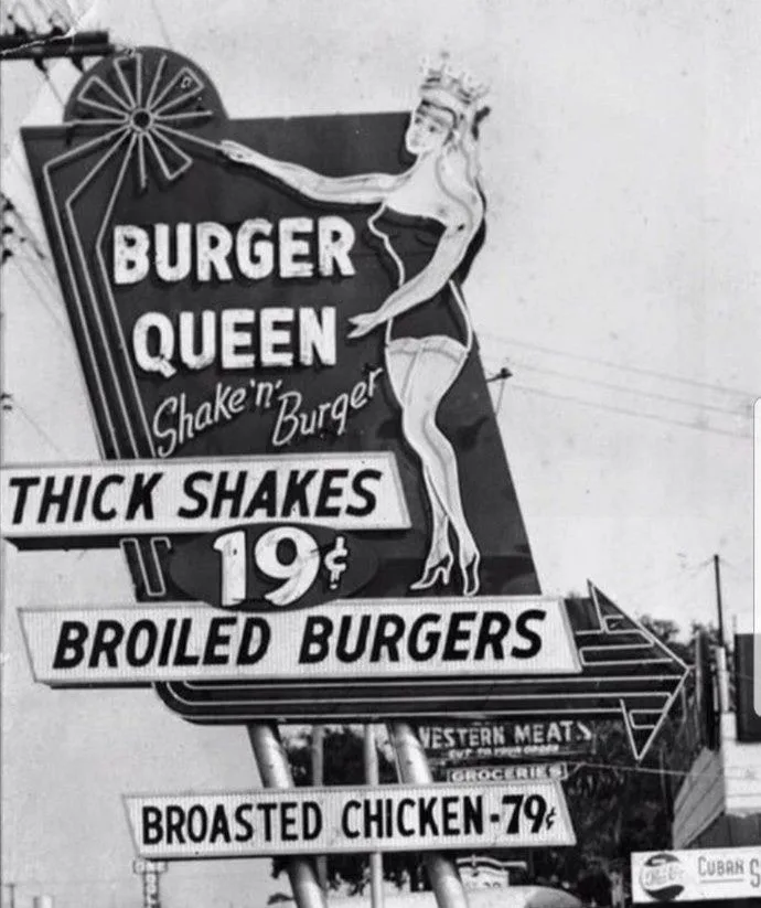 A black-and-white photo of a vintage 'Burger Queen' restaurant sign featuring a stylized pin-up woman in a crown and…