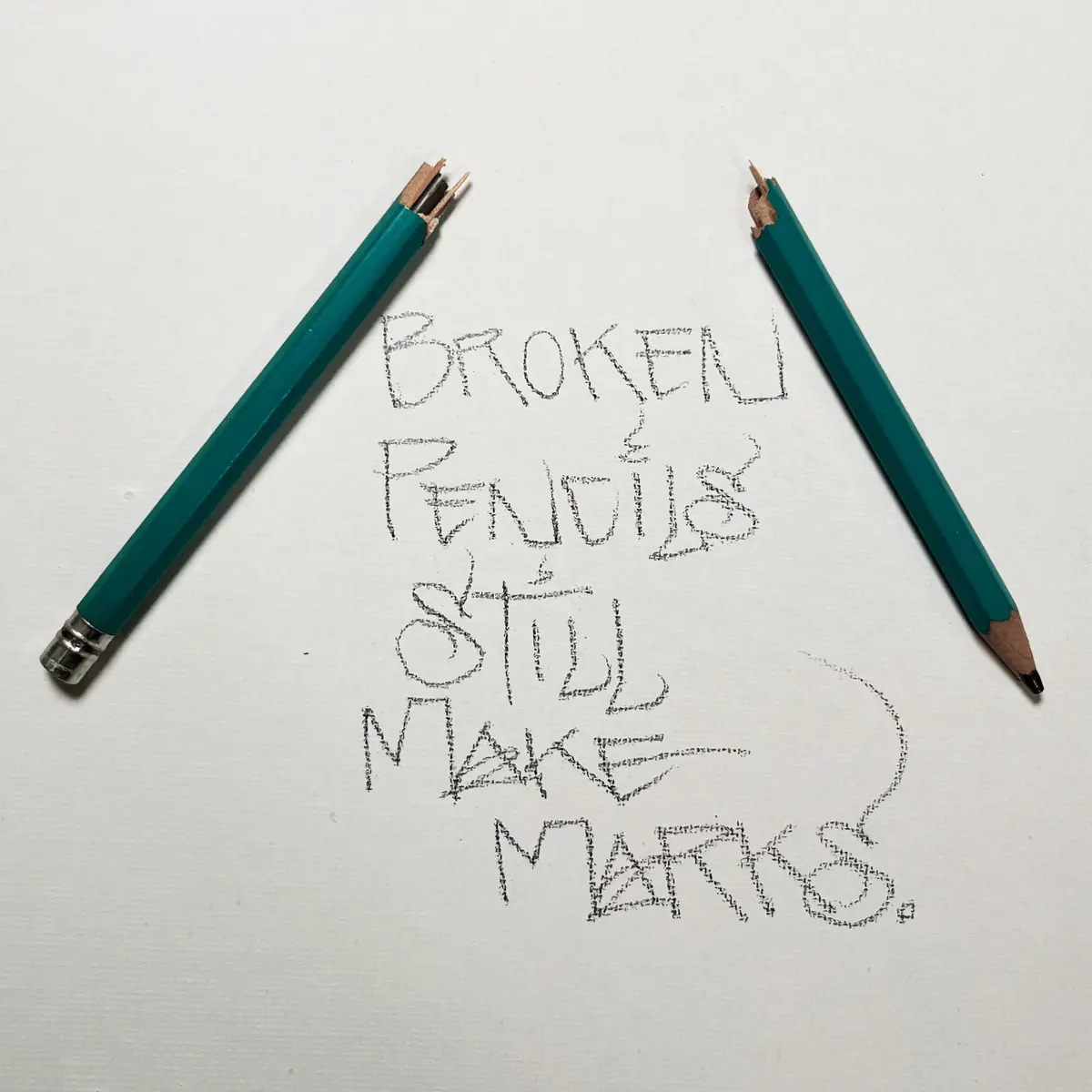Two broken green pencils lie on white paper, one with a snapped tip and the other with a chipped end. Handwritten text in…