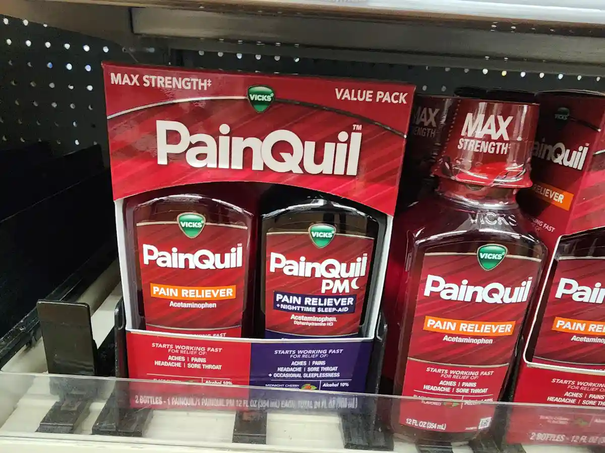 A close-up photo of Vicks PainQuil bottles on a store shelf, showing a red box labeled 'MAX STRENGTH VALUE PACK' containing…