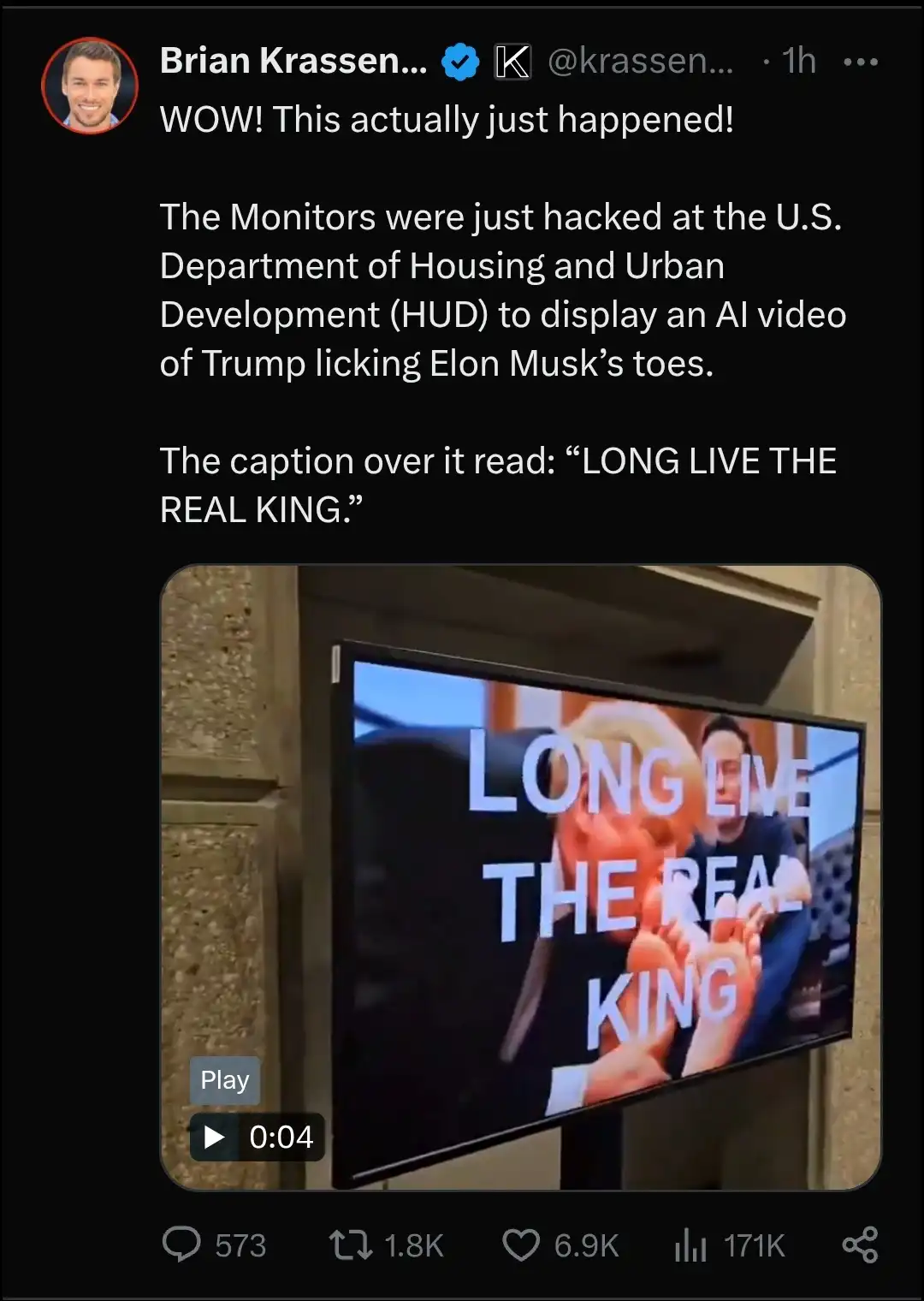 A screenshot of a tweet by Brian Krassen showing a video playing on a monitor inside a government building. The video…