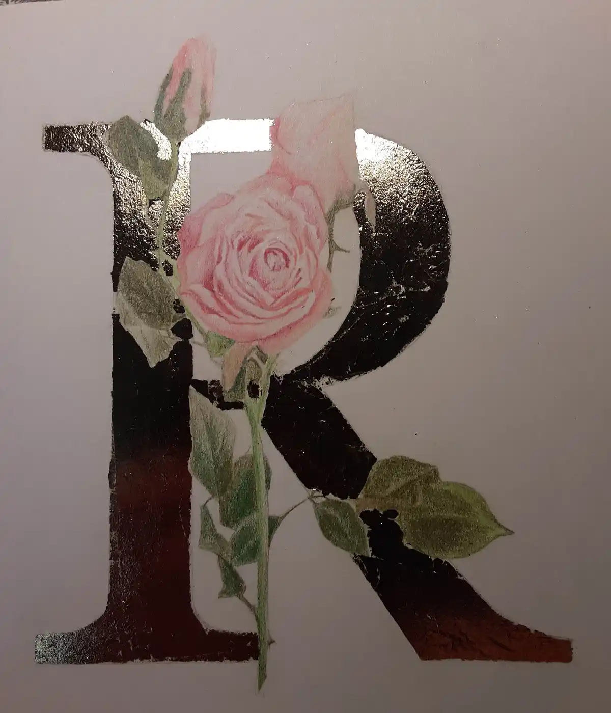 A large, stylized letter 'R' is painted in black and metallic gold with a pink rose and green leaves growing through its…