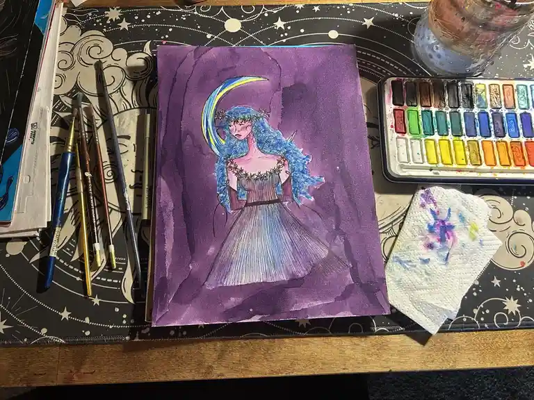 A watercolor painting of a blue-haired woman in a purple dress with a crescent moon behind her sits on a star-patterned art…