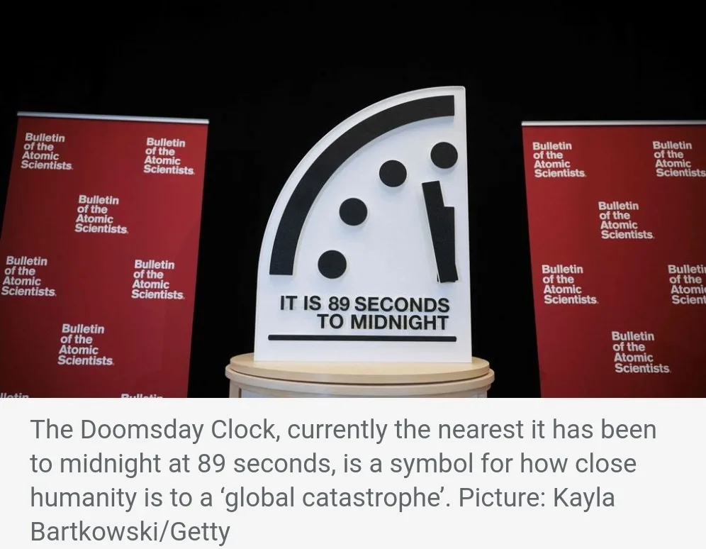 A white, semi-circular Doomsday Clock sculpture with black hour markers and a hand pointing near midnight, displaying the…