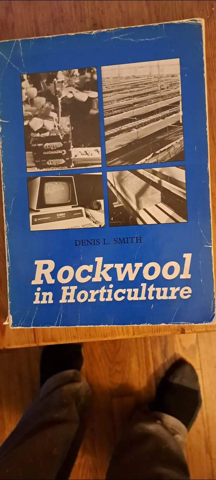A close-up photo of a well-worn blue book titled 'Rockwool in Horticulture' by Denis L. Smith, featuring four…