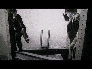 A six-panel black-and-white sequence shows a man in a suit and hat on a steel girder, initially holding a rolled-up…