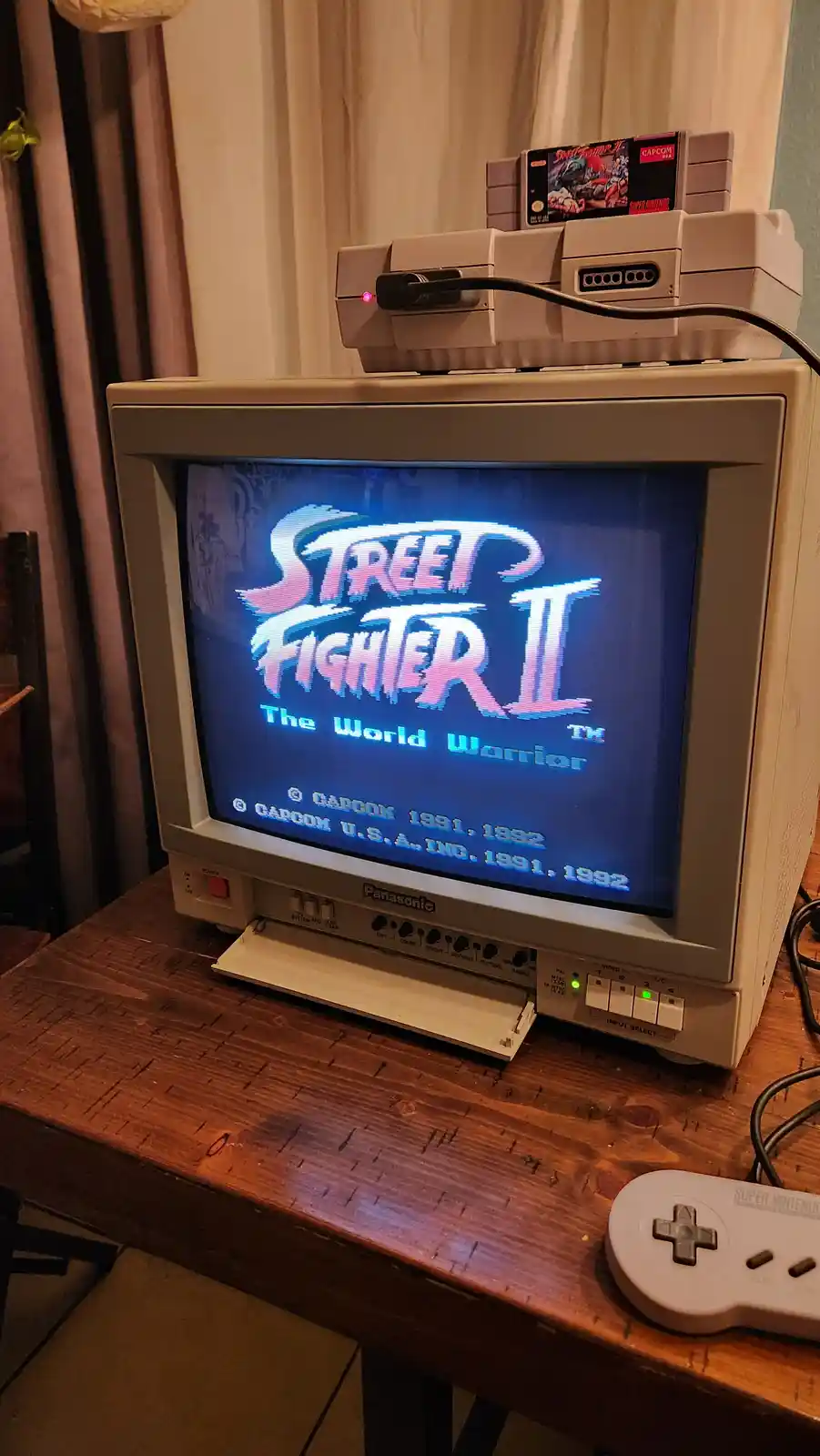 A vintage Panasonic CRT television displays the iconic title screen of 'Street Fighter II: The World Warrior' on a Super…