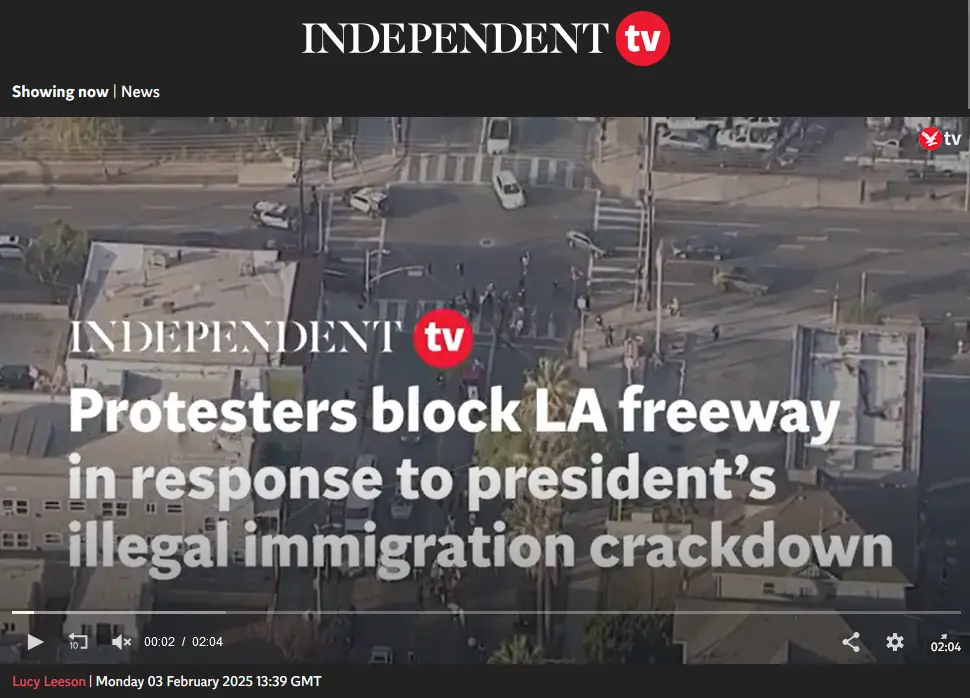 An aerial news broadcast from Independent TV shows a freeway intersection blocked by protesters, with cars and people…
