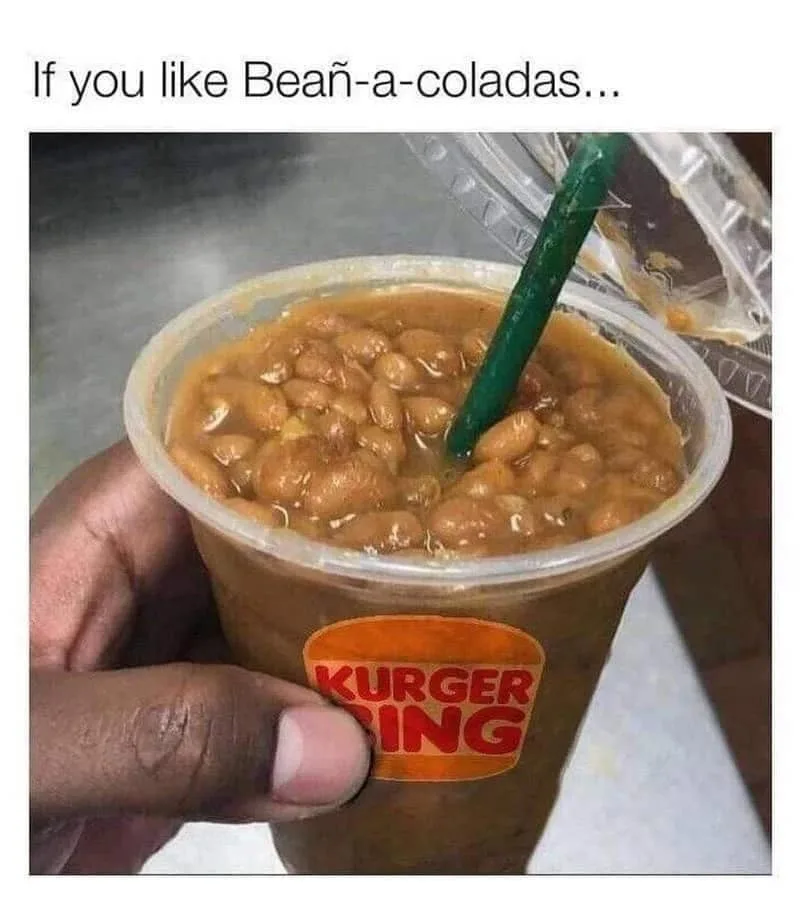 A hand holds a clear plastic cup with a green straw, filled with what appears to be baked beans instead of a beverage. The…
