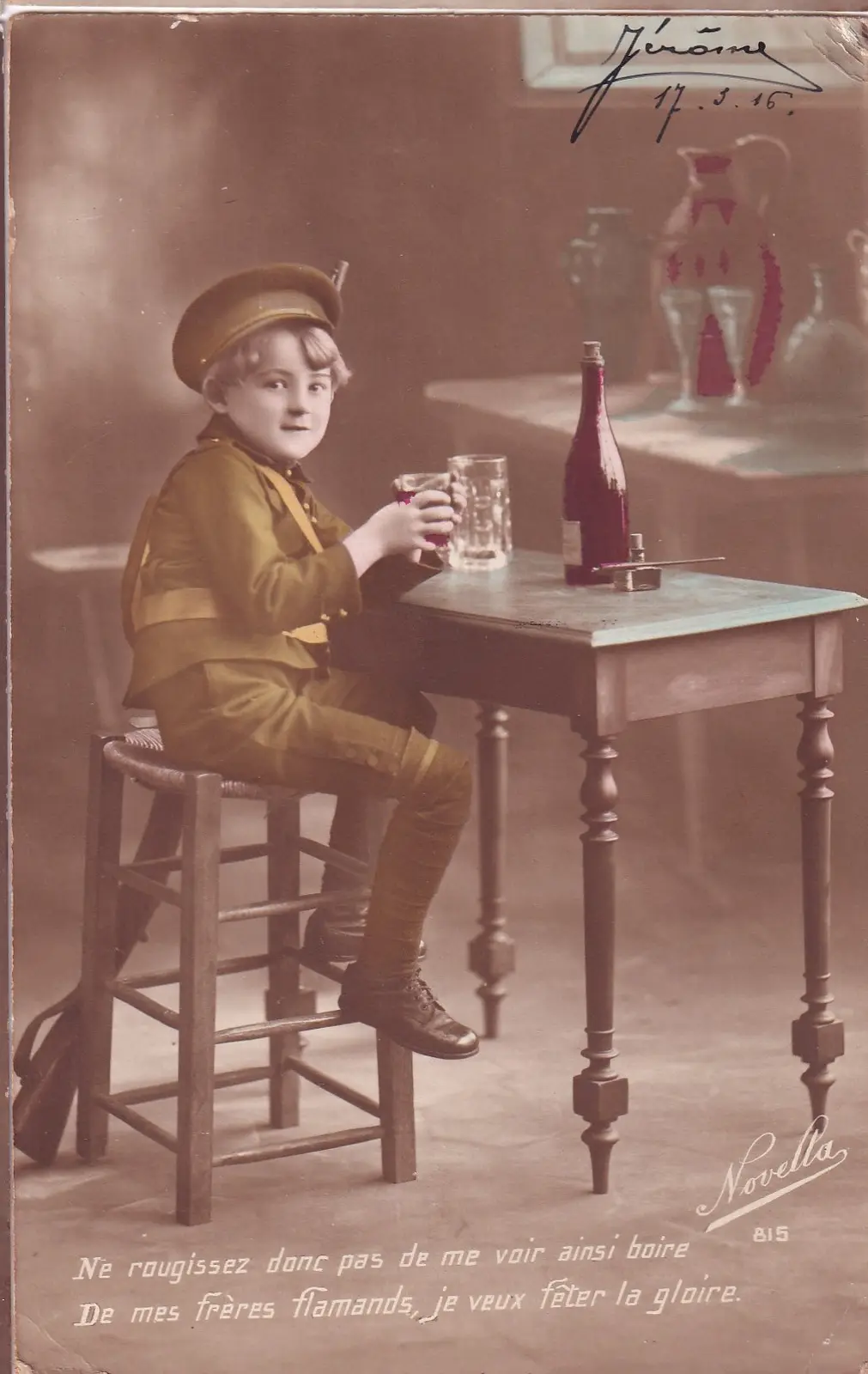 A vintage sepia-toned photograph shows a young boy in a military-style uniform sitting on a stool at a table, holding a…