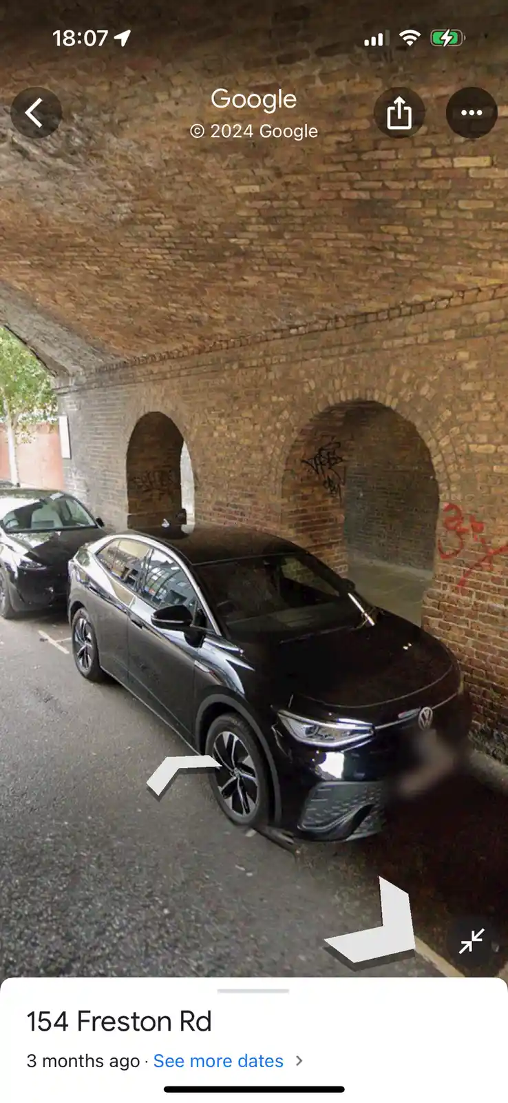 A screenshot from Google Street View shows a black Volkswagen ID.4 parked under a brick archway with graffiti. The car is…