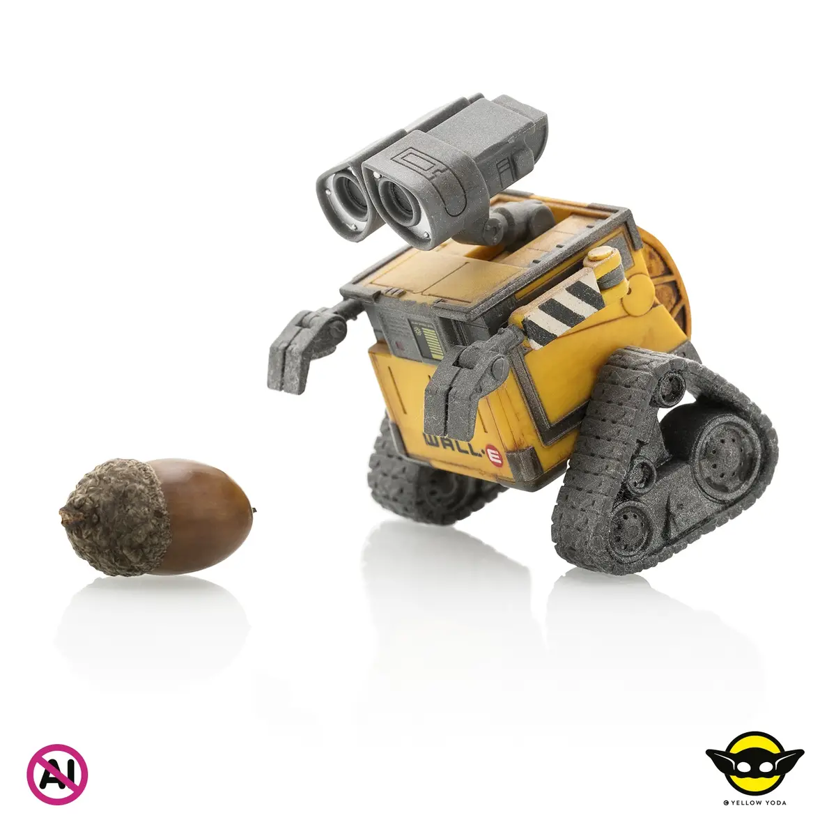 A yellow WALL·E toy robot stands on a white reflective surface, facing an acorn lying nearby. The robot's body is yellow…