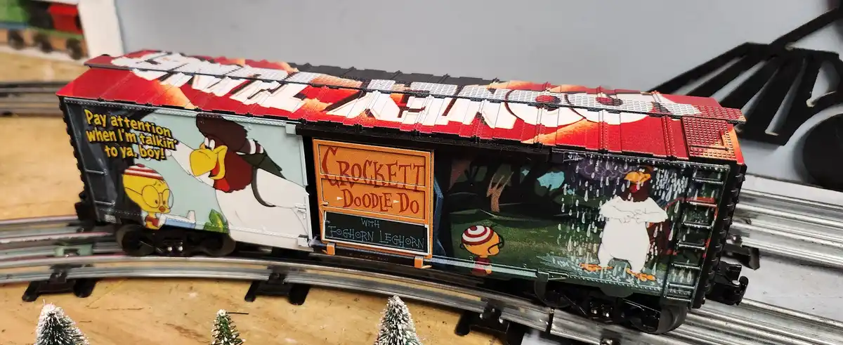A model train car is decorated with scenes from the Looney Tunes cartoon 'Crockett Doodle-Do with Foghorn Leghorn'. One side…
